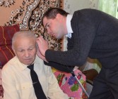 Лікар-отоларинголог допомагає Петру Івановичу одягнути слуховий апарат